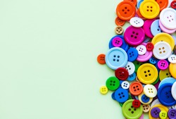 Colored sewing buttons composition on green pastel background. Flat lay with copy space.