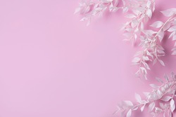 Frame of white branches with leaves on a  pink background