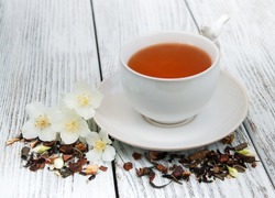 Cup of tea with jasmine flowers on a wooden background