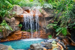 Little pool with a waterfall and hot thermal water surrounded by a tropical garden in Costa Rica, Central America