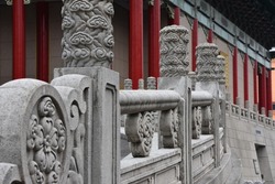 Stone column pillars in typical ancient asian art and traditional hand rails with beautiful flower ornaments in front of old local temple near an oriental garden in the city of Taipei, Taiwan, Asia.