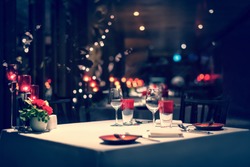 romantic dinner setup, red decoration with candle light in a restaurant. Selective focus. Vintage color.