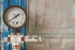 The rusty antique water meter decorated on the vintage door