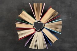 Love reading concept. Books and little wooden heart blackboard with space for text.