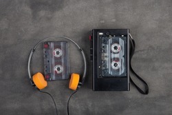Music listening concept. Vintage cassette tape, audio player and headphones close-up on grey concrete background, top view.