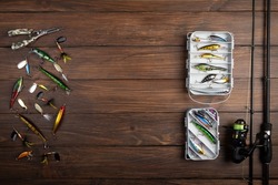 Fishing tackle - fishing spinning rod, hooks and lures on vintage wooden background. Active hobby recreation concept. Top view, flat lay. Copy space for text