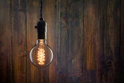 Vintage incandescent Edison type bulb on wooden wall