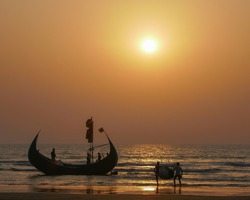 Fishermen preparing for expedition at sunset on traditional wooden fishing boat known as moon boat on beach near Cox's Bazar in southern Bangladesh