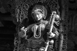 Stone Sculpture of Female (Madanikas) Musician  with selective focus, 12th century Hindu temple, Ancient stone art and sculptures in each pillars, Chennakeshava Temple, Belur, Karnataka, India.