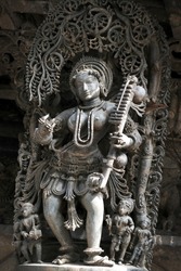 Stone Sculpture of Female (Madanikas) Musician  with selective focus, 12th century Hindu temple, Ancient stone art and sculptures in each pillars, Chennakeshava Temple, Belur, Karnataka, India.