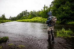 man fly fishing alaska river salmon