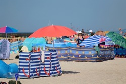 07.19.2022 niechorze, poland, Sun umbrella on a seaside beach in vacation together with a windscreen.