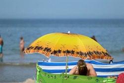 07.19.2022 niechorze, poland, Sun umbrella on a seaside beach in vacation together with a windscreen.