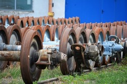 Old rusty wheels of railroad train carriages. Axles.