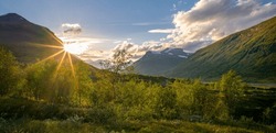 Sun setting behind the mountain in remote Arctic valley. Sarek National Park, Lapland, Sweden. Sun star. Hiking in remote wilderness of Laponia. Sunset in the mountains.