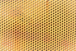 Perforated metal sheet. Peach background. 