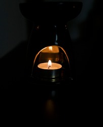 Candle lit in a candle holder with reflection in a dark room