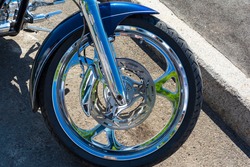 motorcycle brake disc on the front wheel, brake caliper and tire, shining chrome.