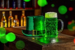 Mugs of green beer, ale on the bar counter. Holiday of Ireland on St. Patrick's Day in irish pub, bar. Festive Leprikon's green hat. National tradition of carnival celebrating March 17.