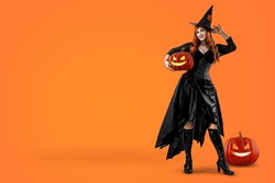 Witch on Halloween with pumpkin Jack-o'-lantern. Female wizard fairy character for All Saints' Day. Fantasy gothic red-haired Vampire girl in black dress. Enchantress dressed in carnival costume