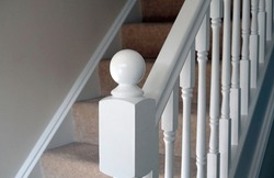 A freshly painted white staircase with carpet on the stairs in a modern home.