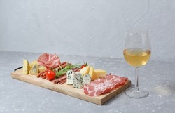 Cheese and a glass of white wine on a grey background. Different cheeses on a wooden board. Cheese set. Empty tablecloth for product montage. Free space for your text