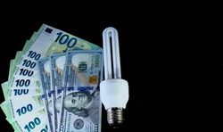 Close-up of euro, american dollar and economy lamp on black background.
High quality photo. Income and business concept.