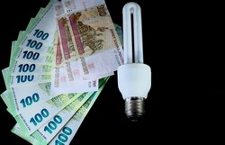Close-up of euro, Russian ruble and economy lamp on black background.
High quality photo. Income and business concept.