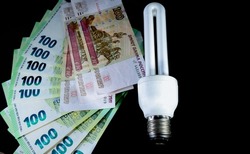 Close-up of euro, Russian ruble and energy saving light bulb on black background.
High quality photo. Income and business concept.
