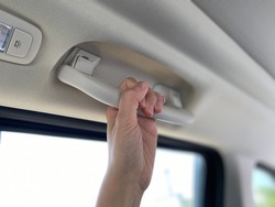 Hand holding the car handle on passenger side. Safety concept in the car. Equipment for the handle, which is installed in ceiling.