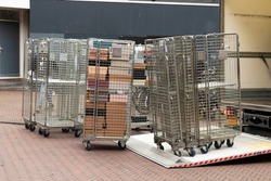 Roll containers or roll cage trolleys  on the road unloaded from a truck with open flap.