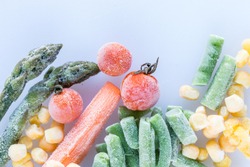 frozen vegetables: cherry tomatoes. asparagus, corn, baby carrot, french beans, peas  on white cutting board, top view, macro