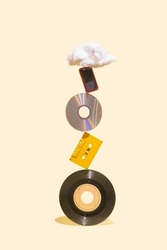 EP vinyl records, cd, cassette tape, CD, MP3 player and cotton cloud shaped prop on the top of each other. History of music mediums concept made on beige background.