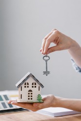 a beautiful small model of a house in women's hands, a house in miniature for an architectural project or a design site, a new house or apartment, a dream about your real estate, the keys to the house