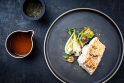 Modern Thai fried cod fish filet with bok choi and mushroom as top view on a plate 