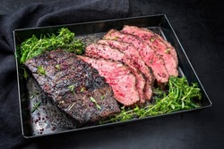 Traditional Commonwealth Sunday roast with sliced cold cuts roast beef with vegetable broccoli and salt as closeup on a rustic metal tray 