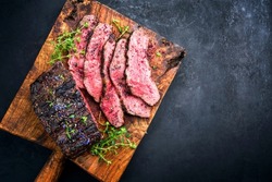 Traditional Commonwealth Sunday roast with sliced cold cuts roast beef with thyme and salt as top view on a rustic wooden cutting board with copy space right