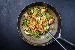 Traditional stir-fried Thai phak kung with king prawns, vegetable and noodles served as top view in a classic design wok