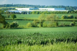 new built distribution warehouse building with farm fields in foreground in england uk