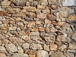 Natural rustic textured brown background. Wall made with piled stones