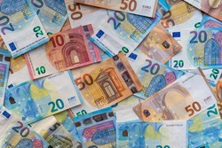 Pile of banknotes on the table in denominations of twenty euros, fifty euros, ten euros, five euros. Background of mixed euro banknotes