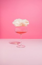 Romantic feelings composition with wine glass and cloud on pastel pink background. Alone for Valentine's Day concept.