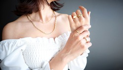 Woman Jewelery concept. Woman’s hands close up wearing rings and necklace modern accessories elegant life style with copy space for text and background. 