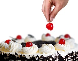 Hand placing the cherry on the cake with white background.