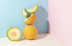 Minimal abstract creative summer fruit scene made of slices of juicy, fresh melon standing on isolated pastel beige, pink and blue background with copy space. Aesthetic concept of raw healthy food.