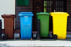 Four colored containers for segregated rubbish. The bins are standing on the street waiting for the garbage truck. Poland, Warsaw.                               