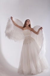 Girl in white dress with angel wings on white background. Angel-woman