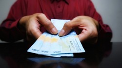 A man's hand is making a payment. Indonesian Rupiah the official currency of Indonesia.  Male hand showing Indonesian Rupiah note. Business and finance concept. Uang 50000 Rupiah. Bank Indonesia