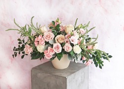     Light airy pink white and green floral arrangement of fresh flowers like roses, spray roses and fresh greenery, marble pink and white background, white vase, Mother's Day.                         