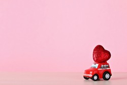 Red heart on a small toy car. The concept of love and Valentine's Day. High quality photo